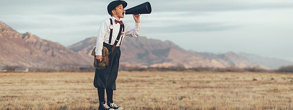 Boy with megaphone in the landscape 