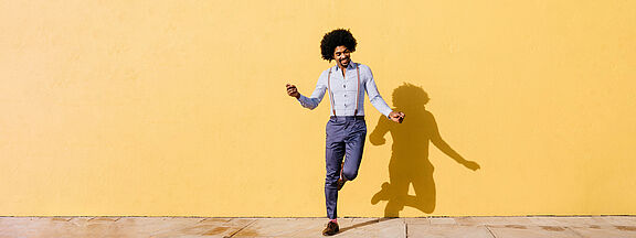 Man dancing in front of a yellow house wall